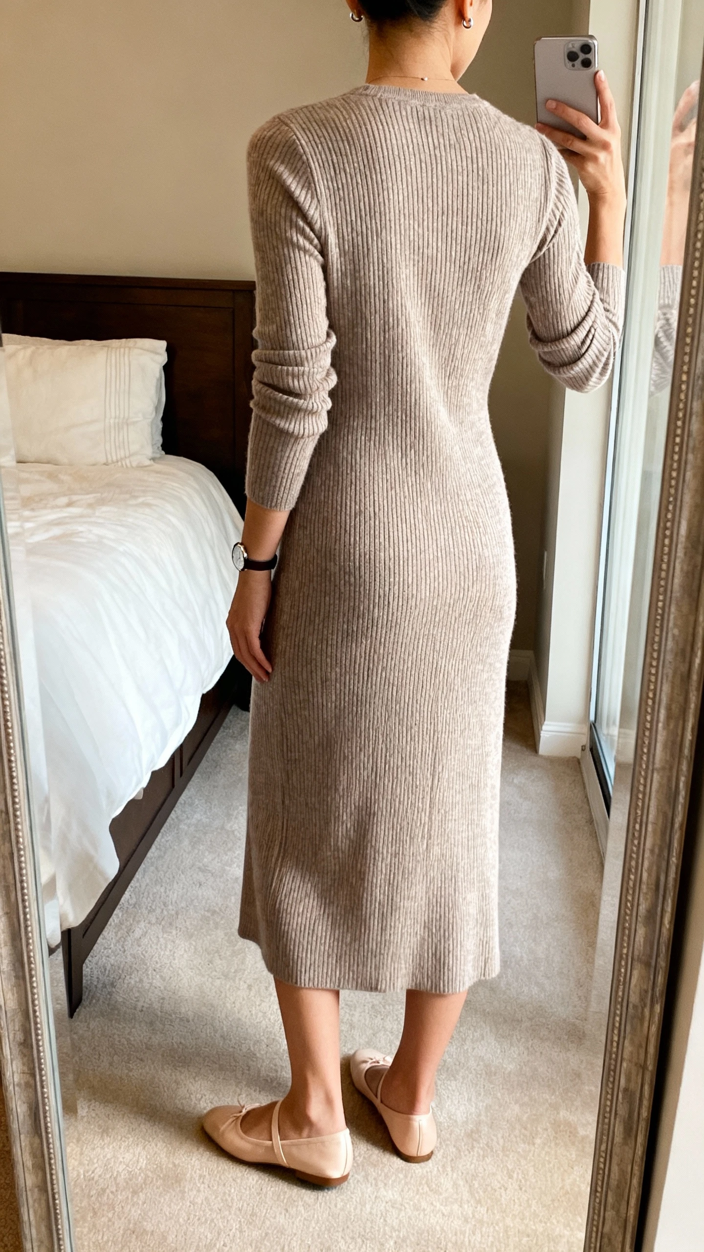 iPhone back-view mirror selfie of a woman wearing a ribbed knit midi dress with long sleeves and ballet flats, minimal stud earrings and a slim watch, face not visible, bedroom mirror, warm indoor lighting, iPhone photo quality.