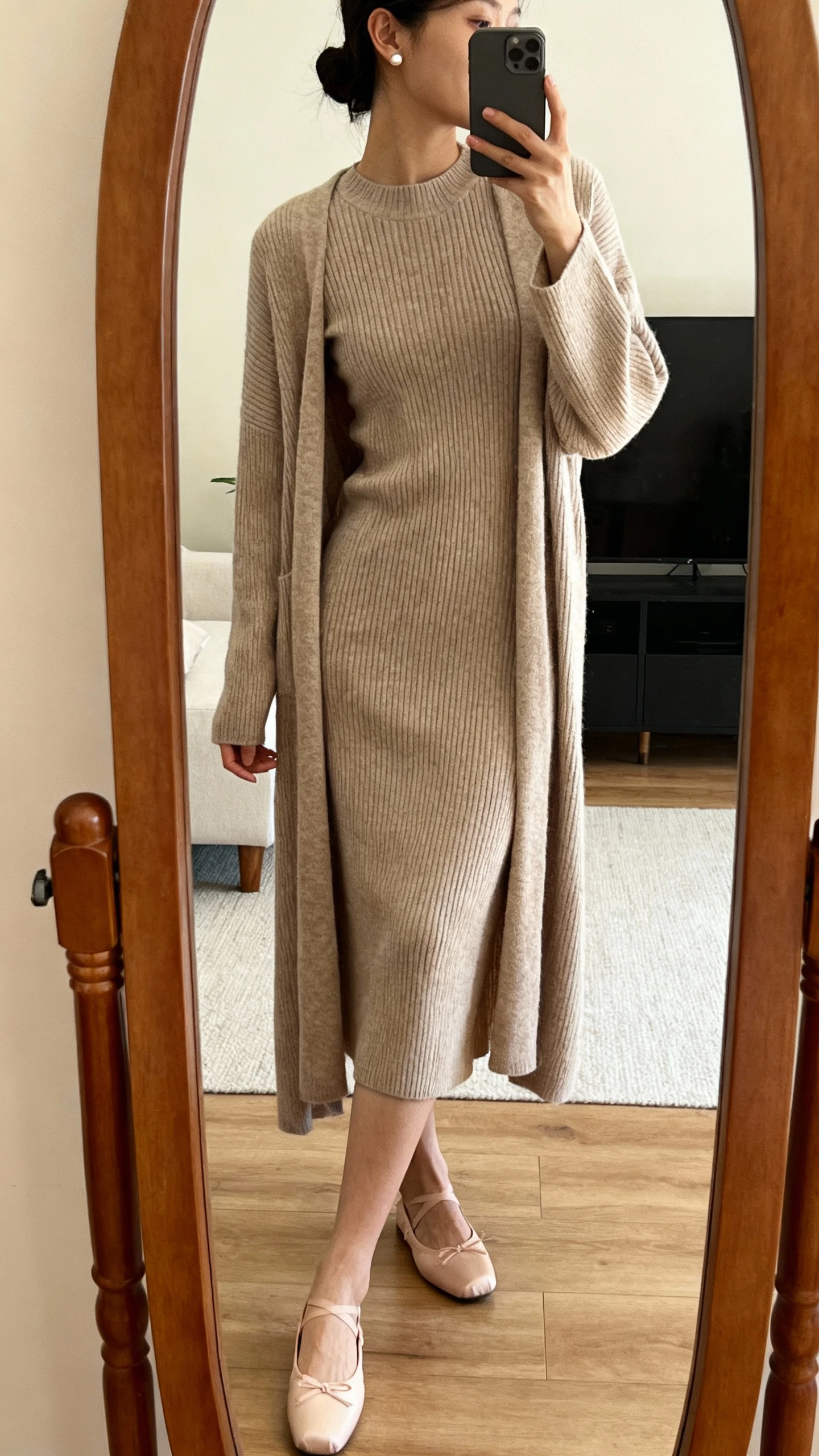 iPhone mirror selfie of a woman wearing a ribbed knit midi dress with a long matching cardigan, styled with ballet flats and stud earrings, face not visible, side angle, living room full-length mirror, warm indoor lighting, iPhone photo quality.