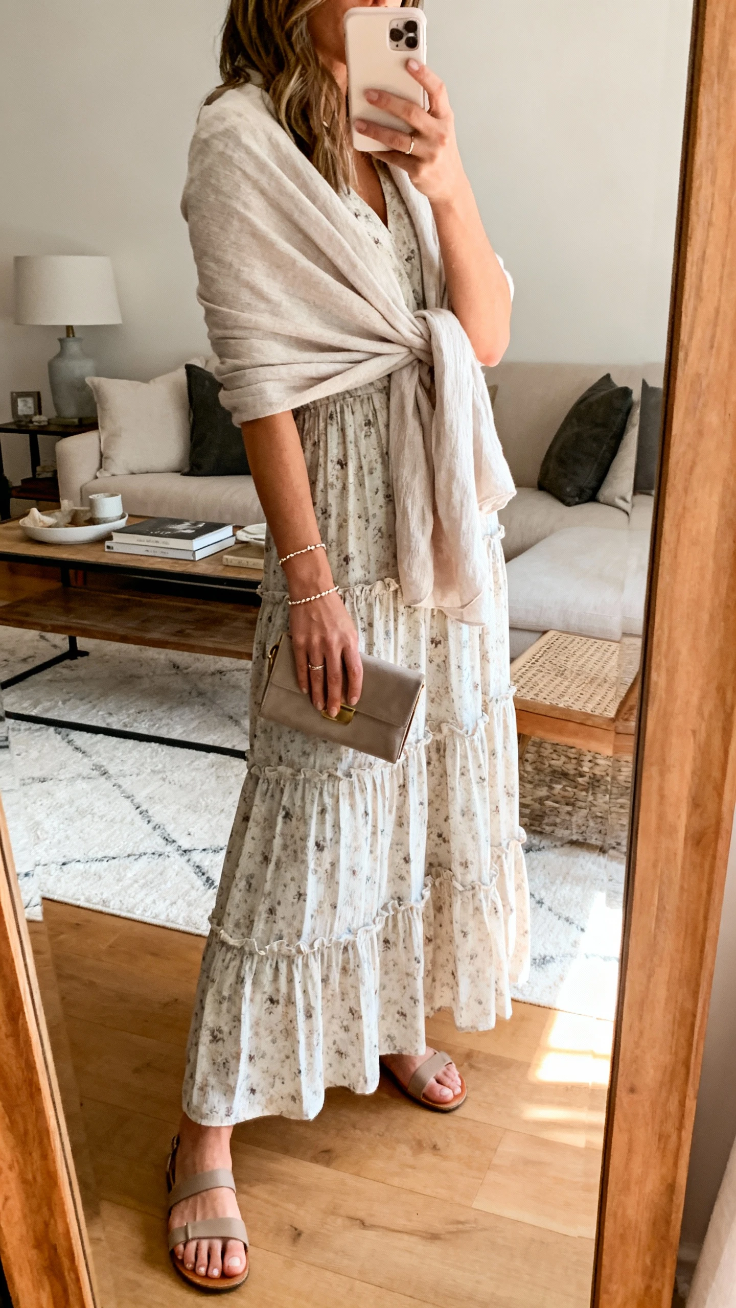 iPhone mirror selfie of a woman wearing a tiered maxi dress with subtle prints and a soft wrap shawl, low sandals, dainty bracelet, and a small clutch, face not visible, side angle, living-room full-length mirror, gentle morning light, iPhone photo quality.