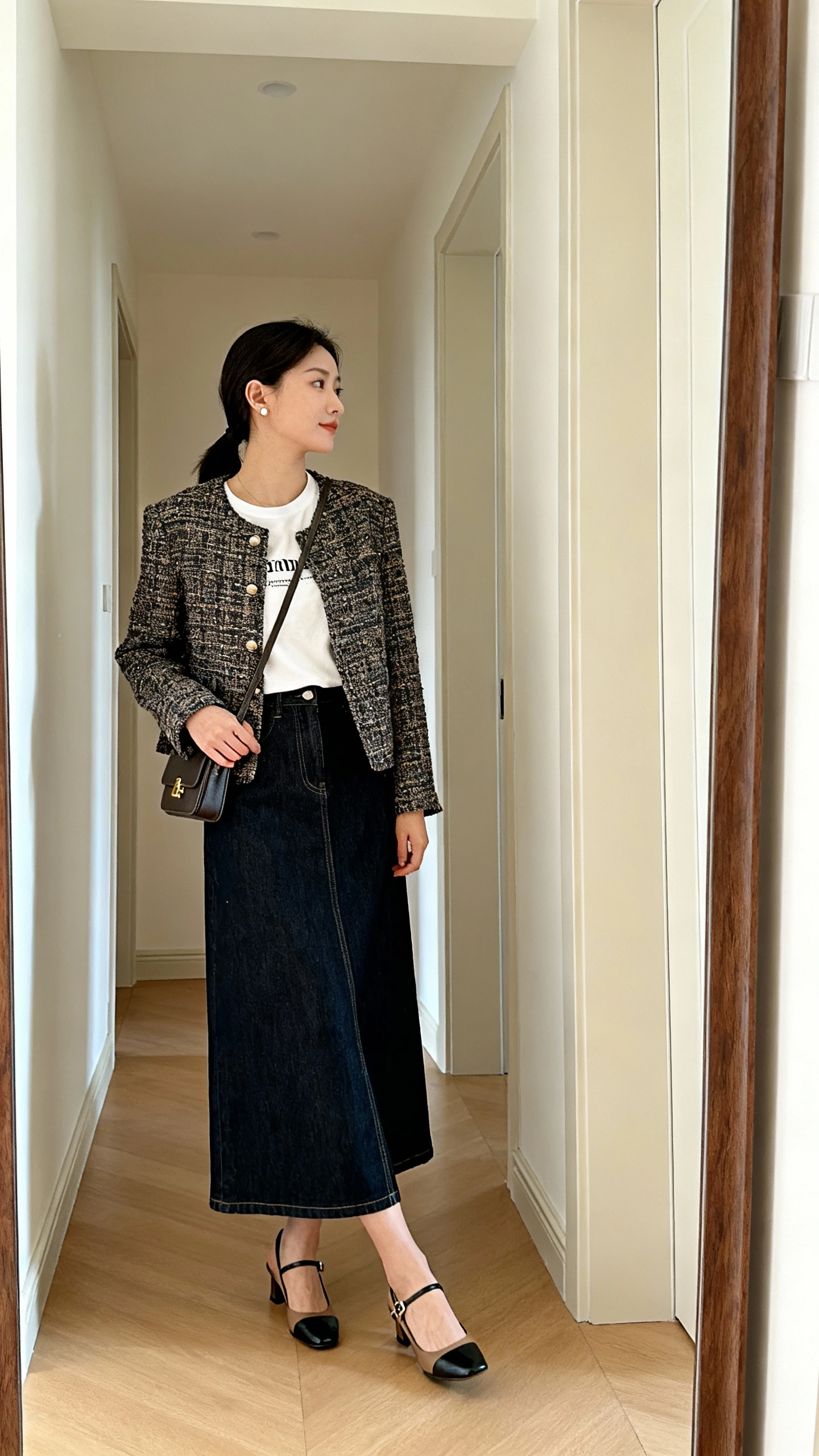 iPhone mirror selfie of a woman wearing a dark denim maxi skirt, tweed lady jacket over a simple tee, slingback heels, small crossbody bag, and minimal stud earrings, face not visible, side angle in a hallway full-length mirror, morning light, iPhone photo quality.