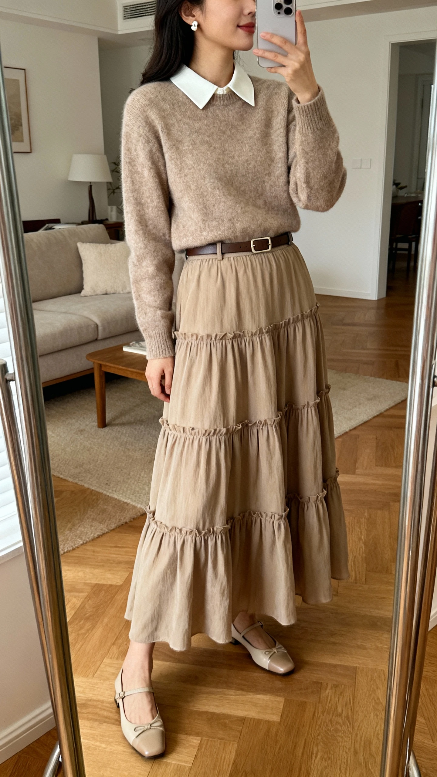 iPhone mirror selfie of a woman wearing a tiered maxi skirt and a collar-sweater with elegant flats, simple stud earrings and a slim belt, face not visible, side angle, living room mirror, warm indoor lighting, iPhone photo quality.