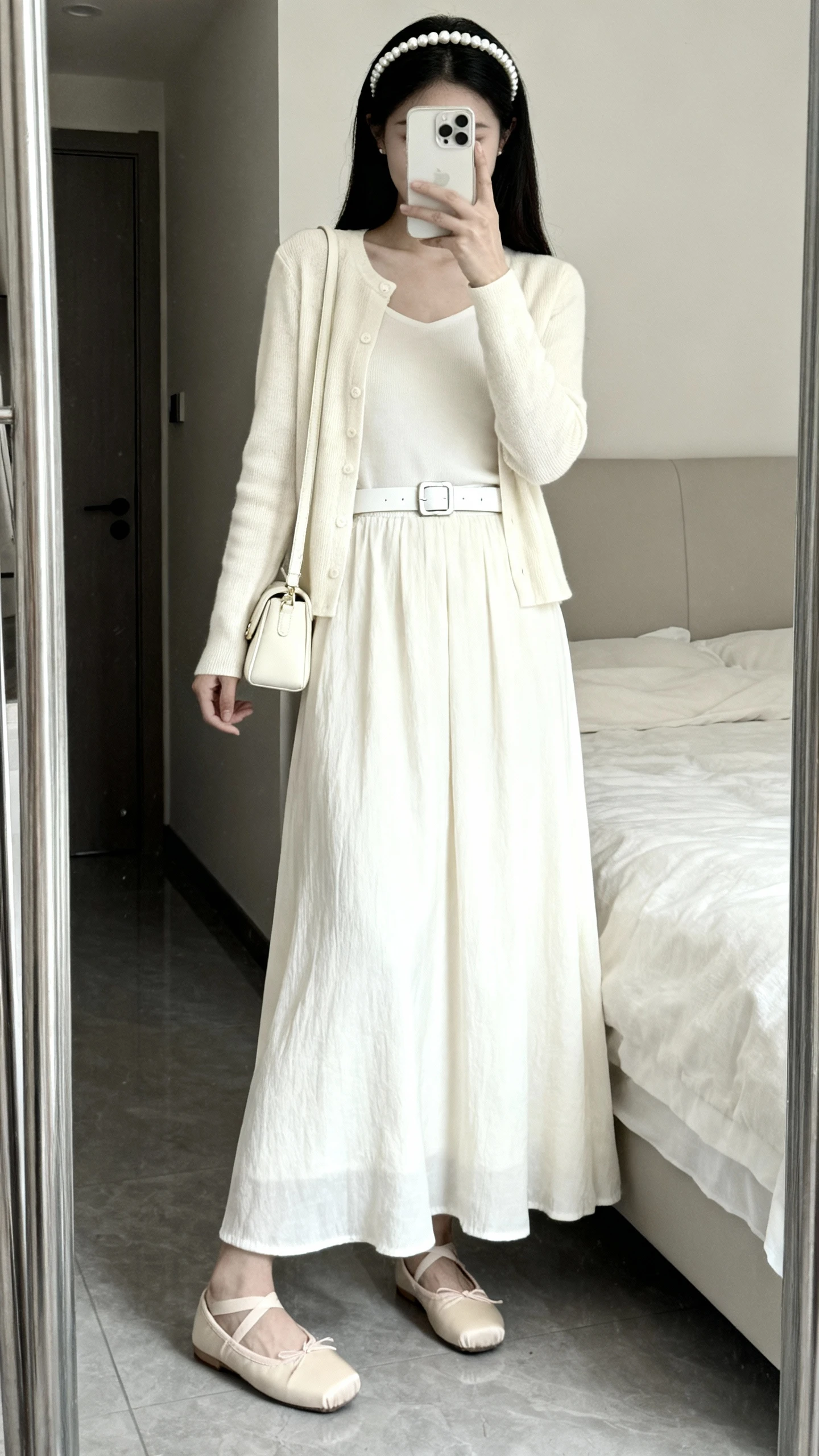 iPhone mirror selfie of a woman wearing an ivory maxi dress with matching cream cardigan and ivory belt for a monochrome look, beige ballet flats, a pearl headband, and a small cream shoulder bag, face not visible, cropped at shoulders, bedroom mirror, soft natural light, iPhone photo quality.