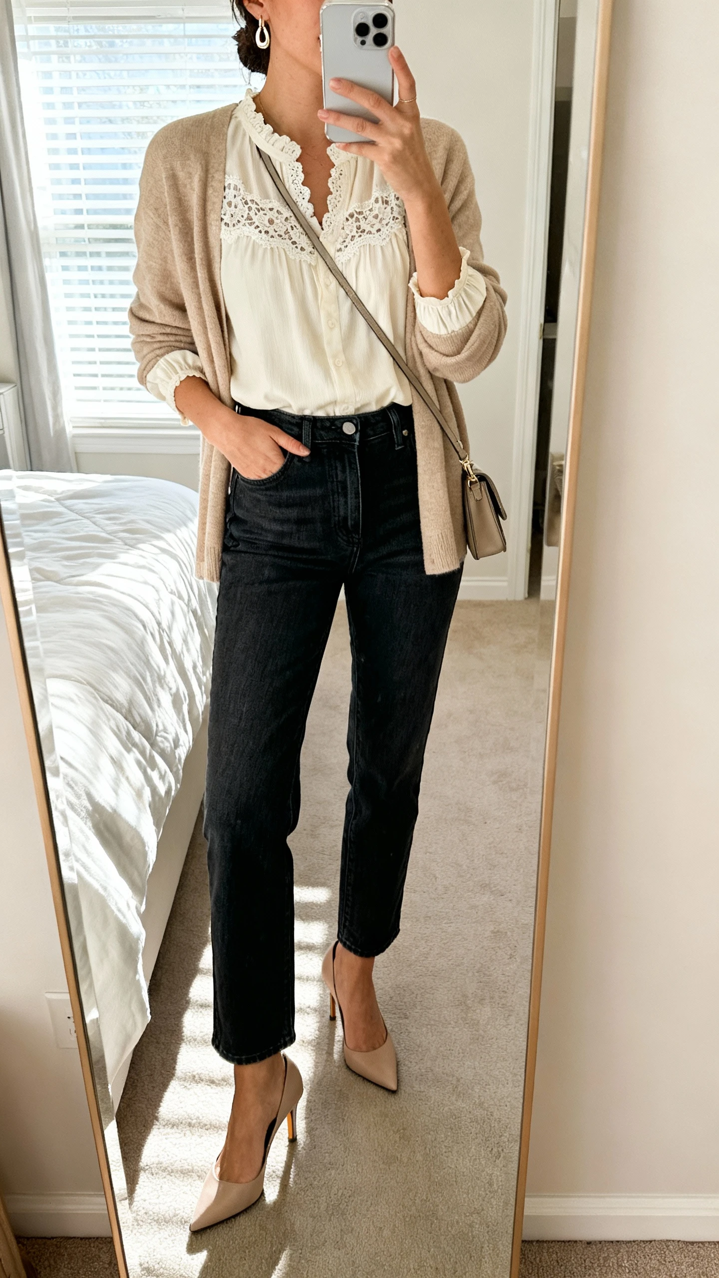 iPhone mirror selfie of a woman wearing dark-wash straight-leg high-rise jeans, a cream lace-trim blouse with modest neckline and sleeves, a soft sand cardigan, kitten-heel slingbacks, and subtle drop earrings with a small crossbody bag, face not visible, bedroom mirror, window light, iPhone photo quality.