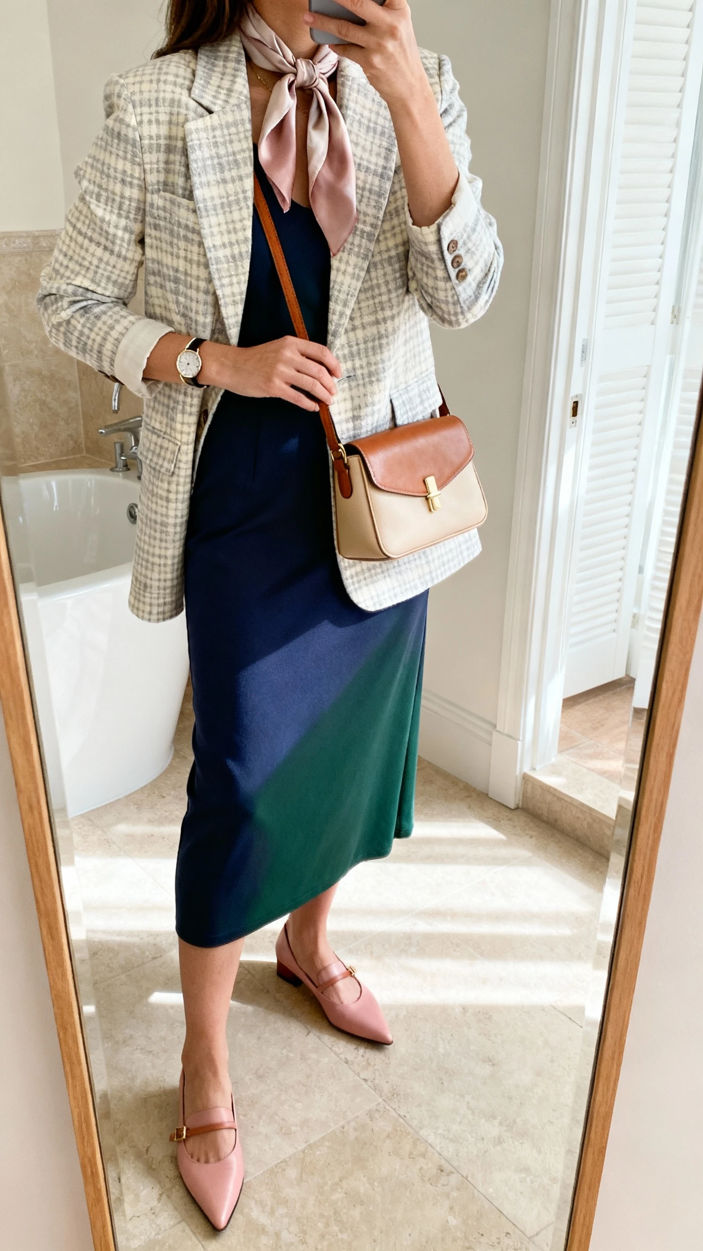 iPhone side-angle mirror selfie of a woman wearing a subtle check blazer in cream/stone or grey/soft taupe over a solid midi dress in jersey/crepe (navy, forest, or soft rose), pointed-toe flats or low slingback heels, a thin bangle or classic watch, a caramel leather tote or beige fitted crossbody, and a tonal silk scarf; face not visible, bathroom mirror, soft indoor morning light, iPhone photo quality.